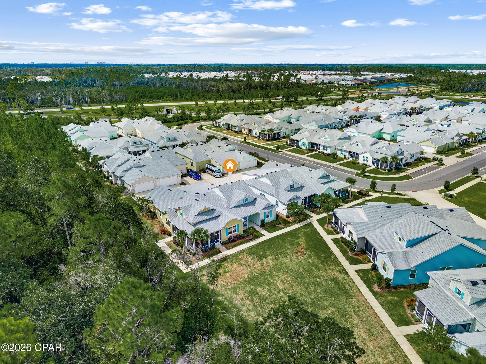 Aerial view of a marked home among neighborhood houses, lawns, and surrounding trees.