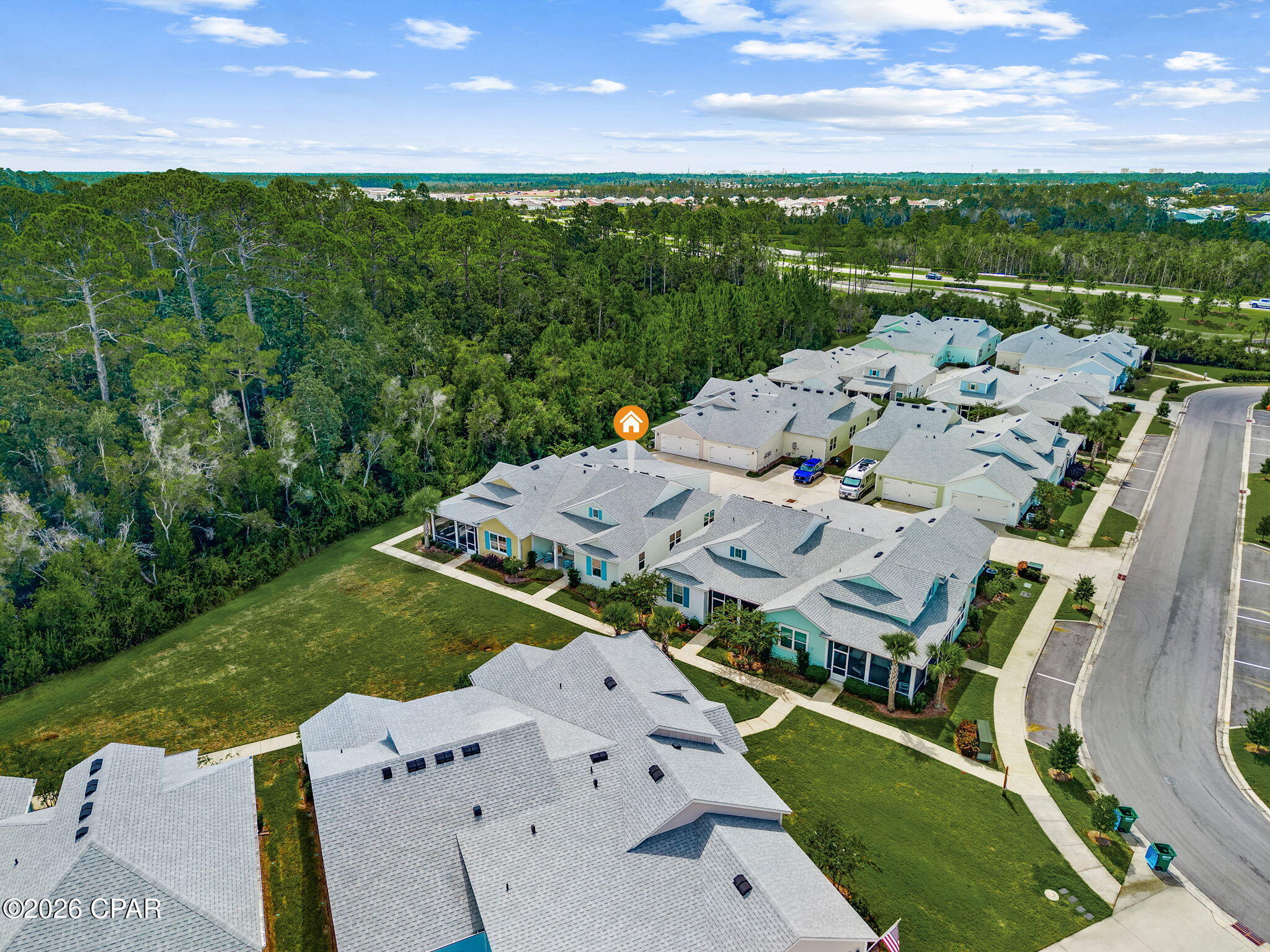 Aerial view of the marked home in a neighborhood bordering dense woods.