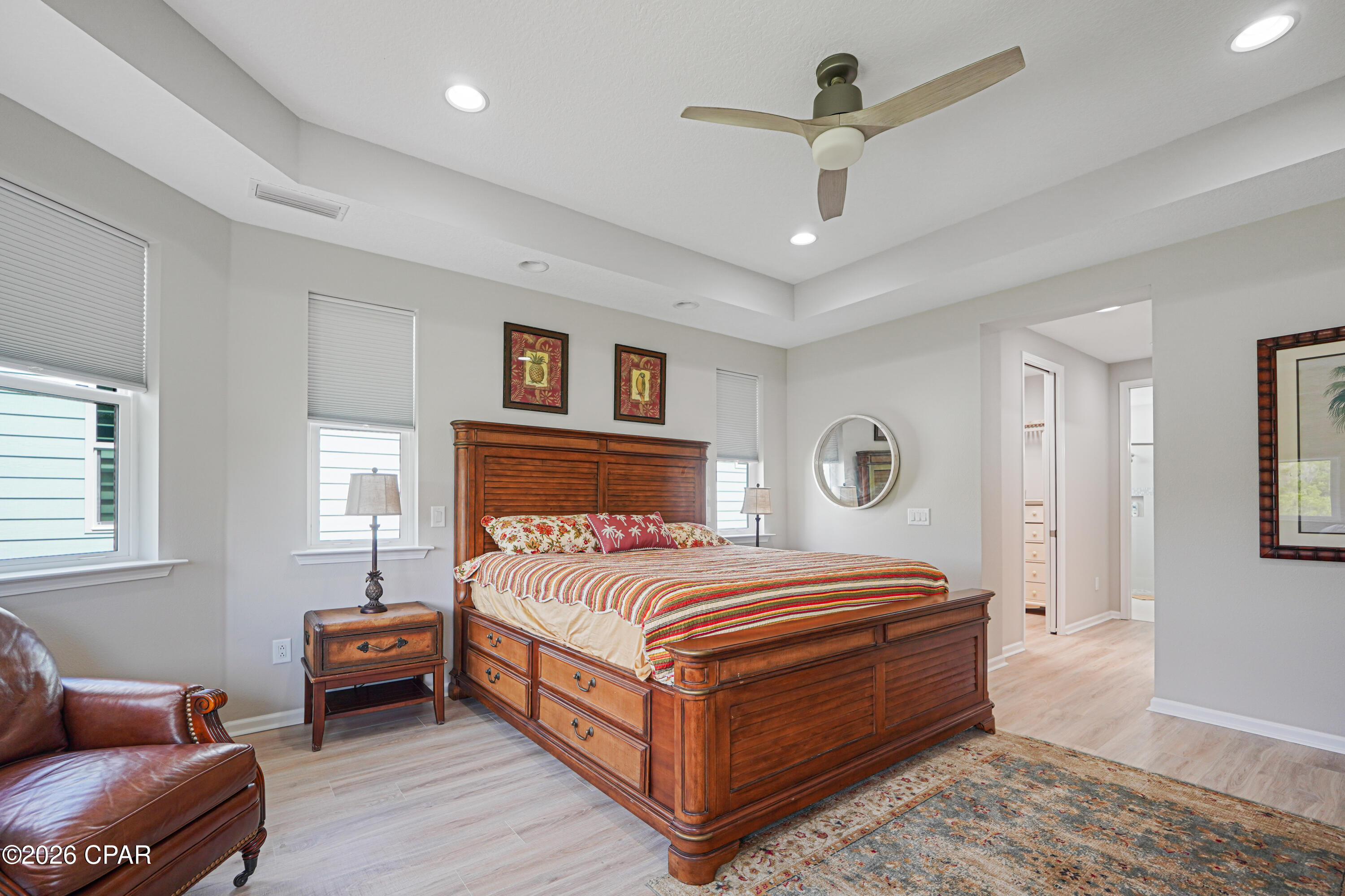 Furnished bedroom with a large wooden storage bed, colorful striped bedding, and a ceiling fan.