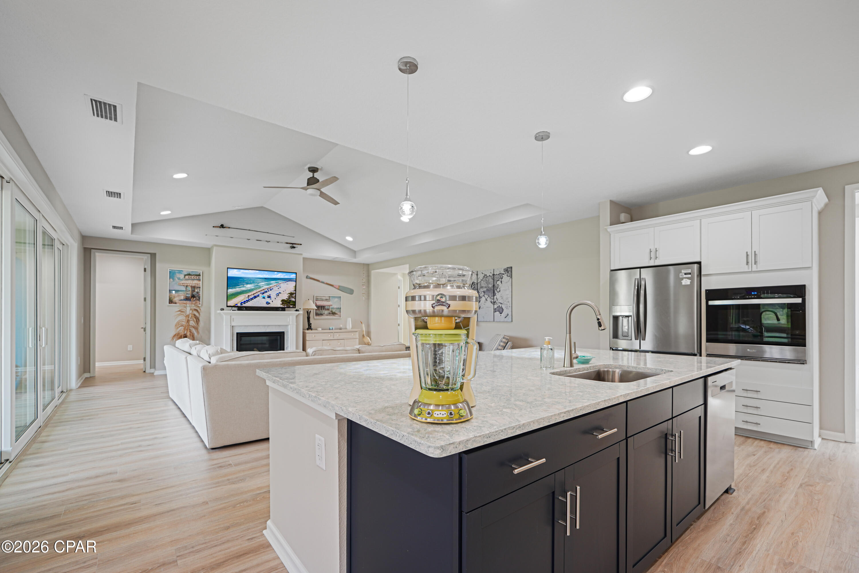 Open-plan kitchen and living room with a large island and blender on the countertop.