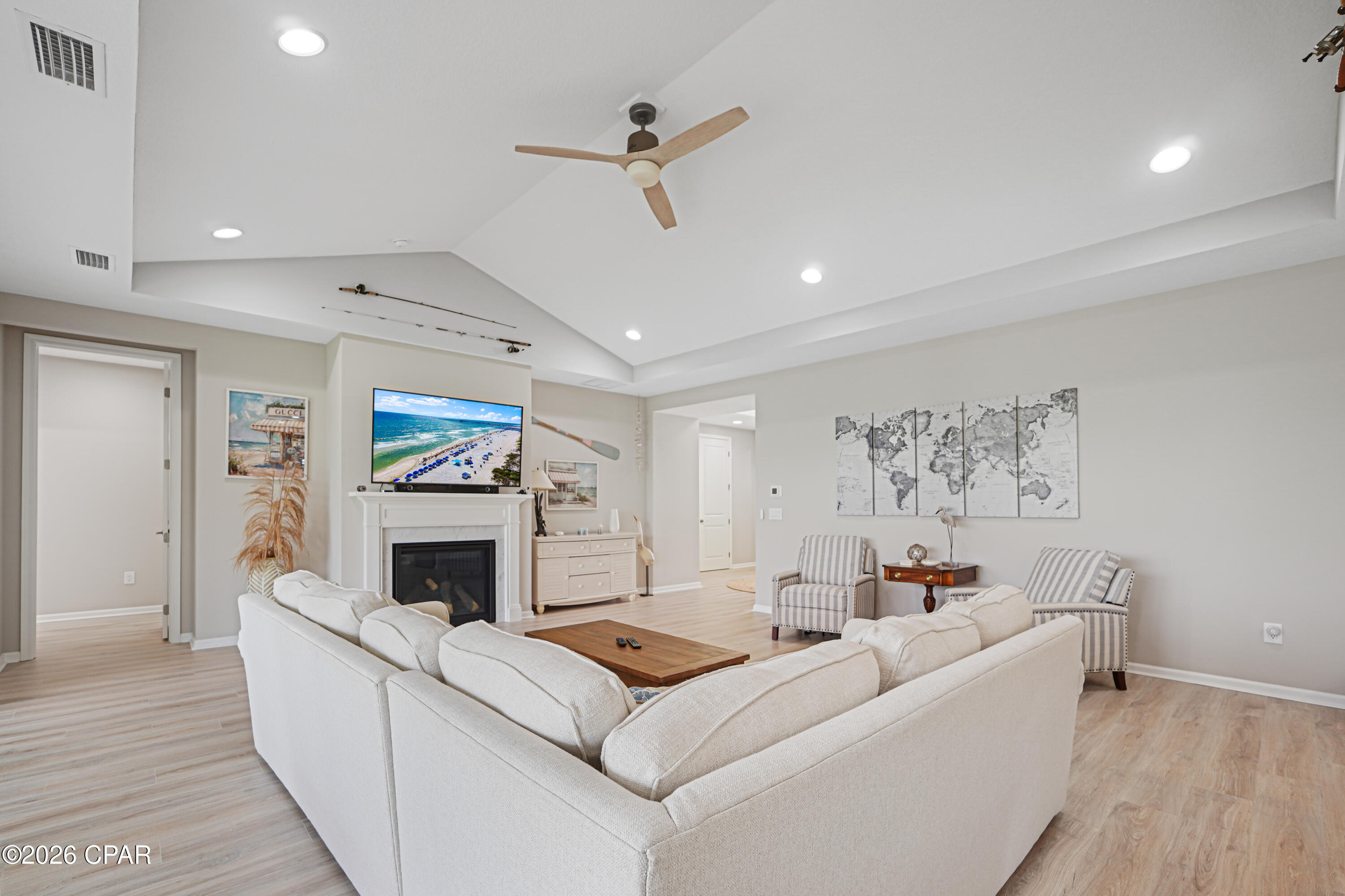 Furnished living room with vaulted ceiling, fireplace, white sectional, and ceiling fan.
