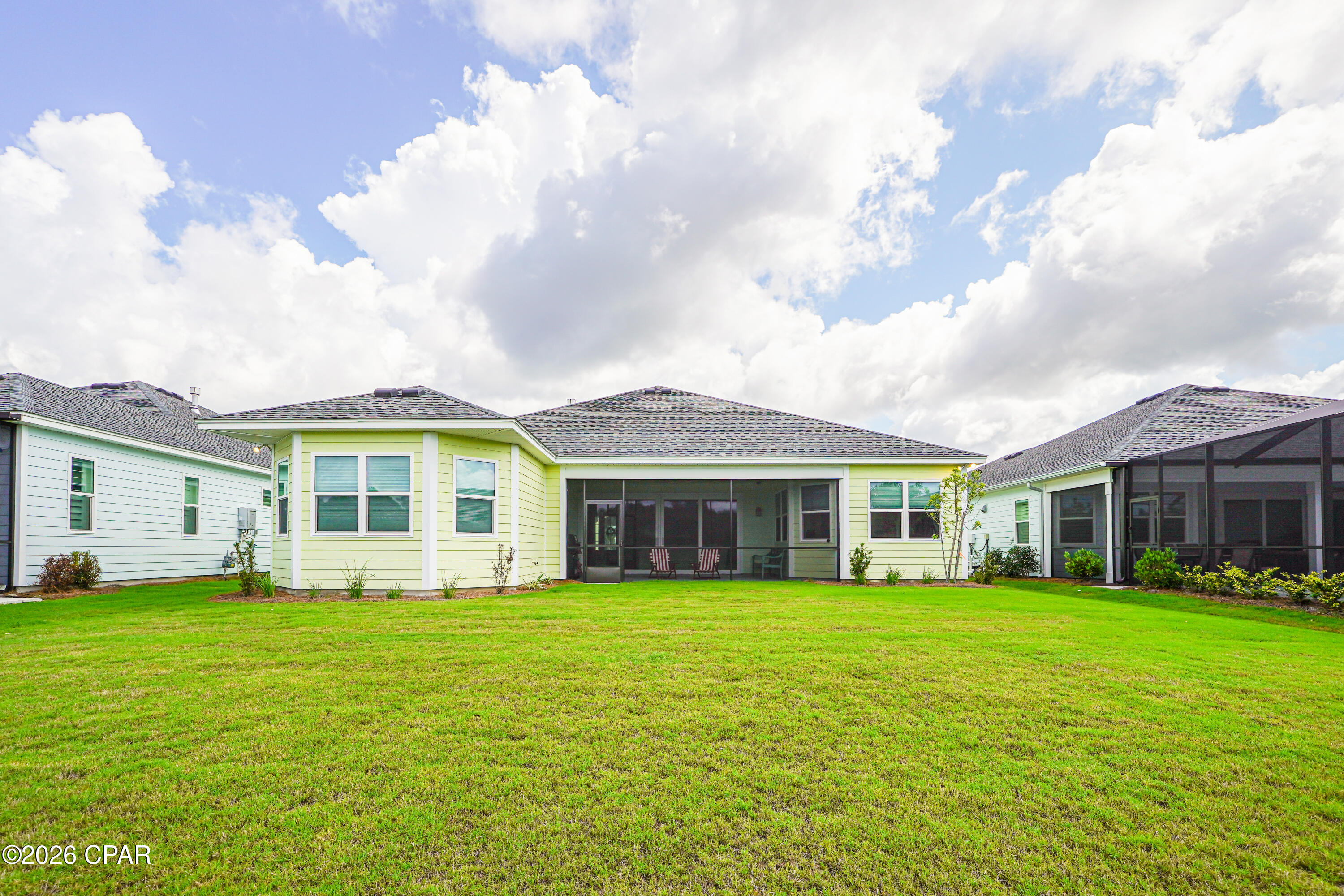 Rear exterior of 9431 Paradise Drive with a wide screened porch and broad lawn.