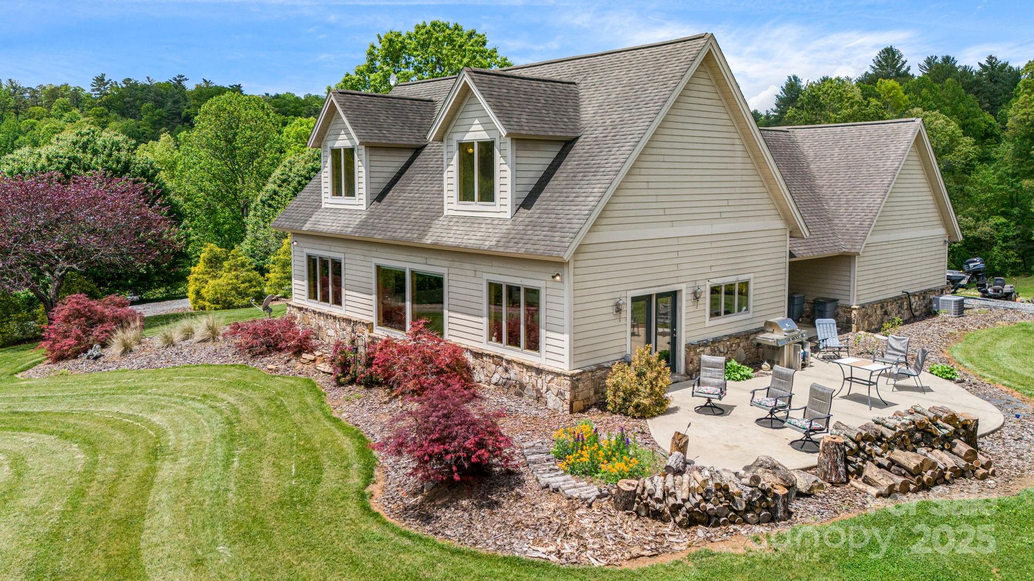 Gabled house with a stone foundation and a furnished patio overlooking landscaped grounds.