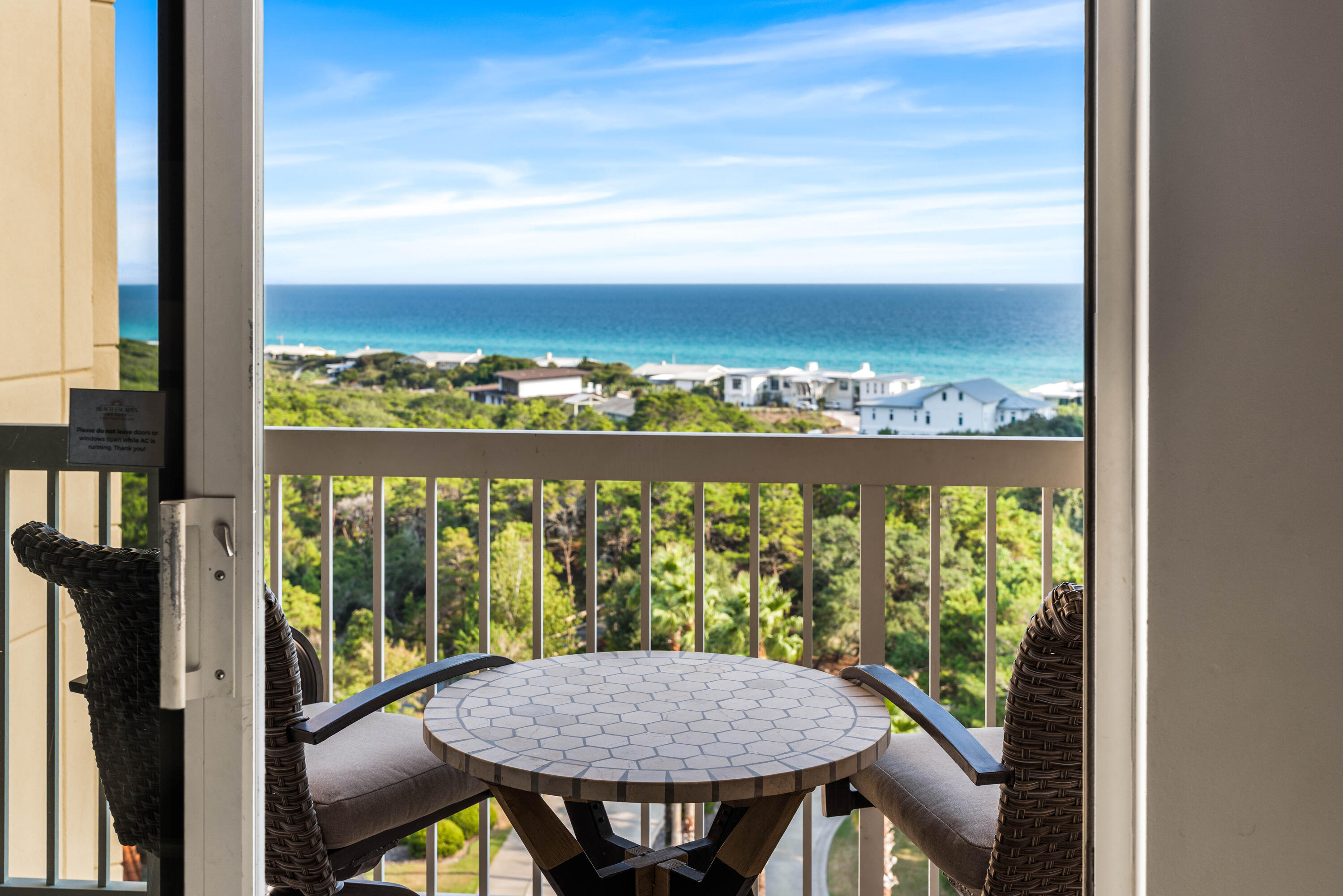Furnished balcony with a tiled table and wicker chairs overlooking the ocean.