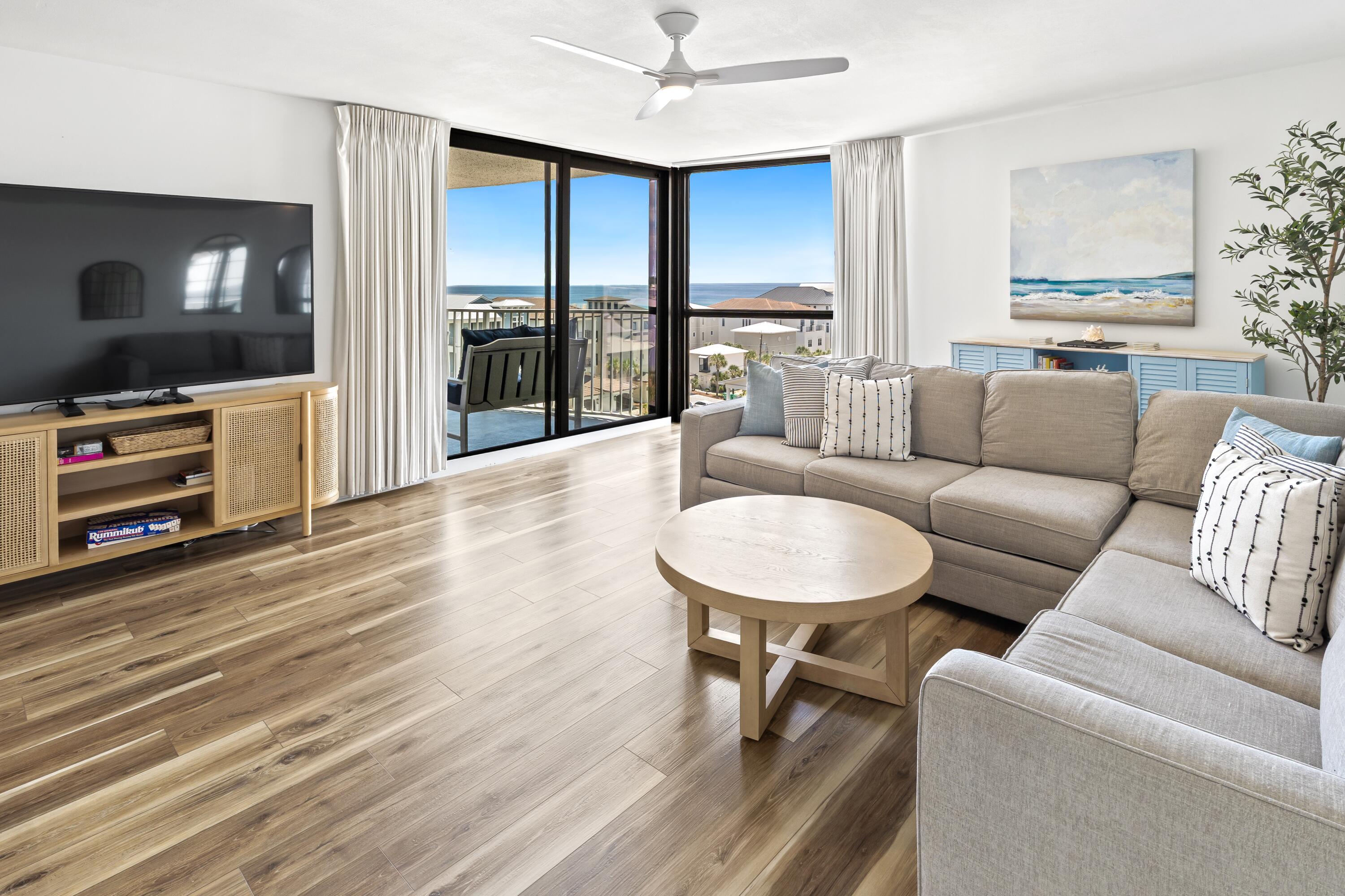 Condo living room with a gray sectional and sliding doors overlooking the ocean.