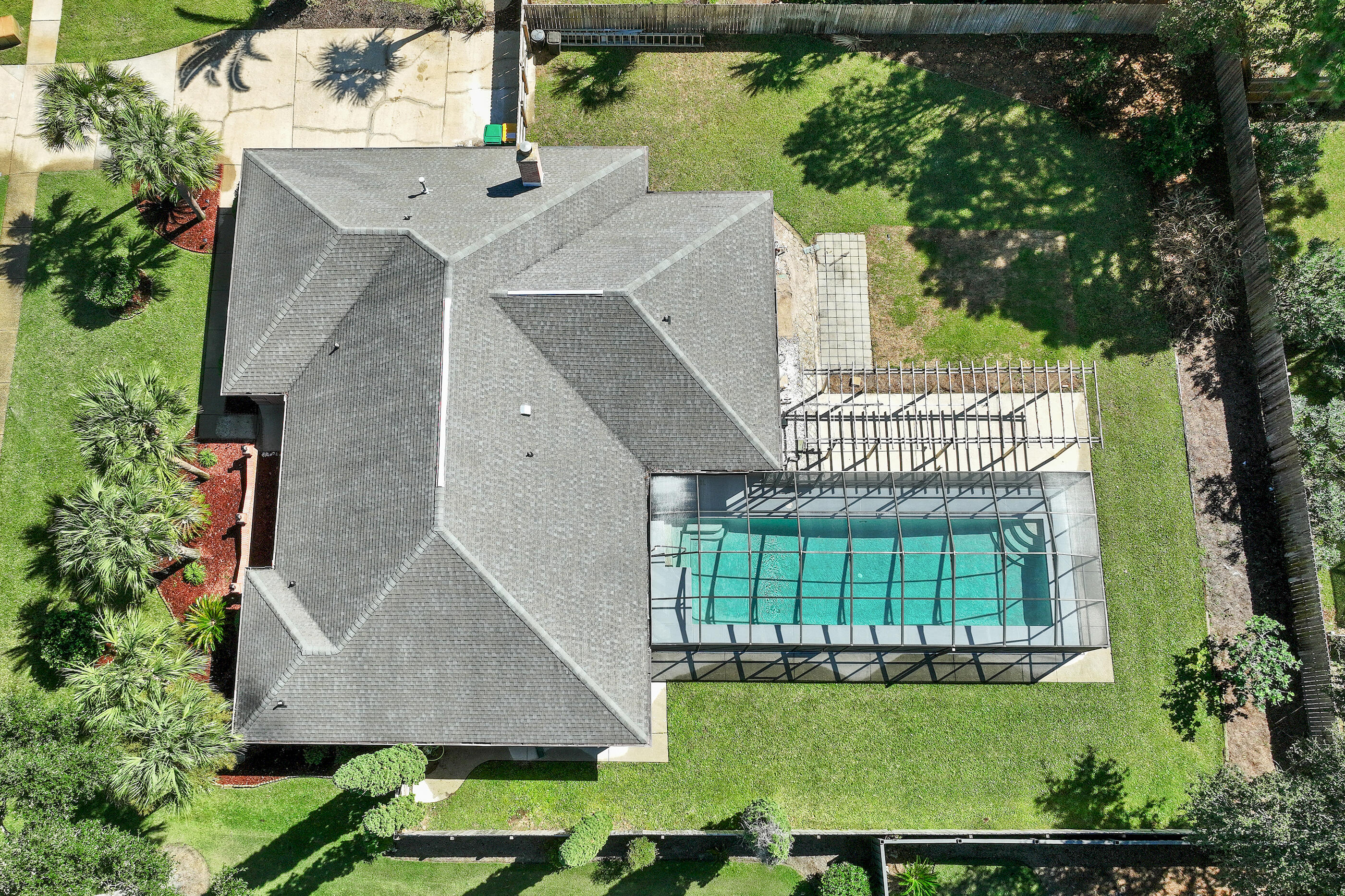 Aerial view of a home with a screened swimming pool and palm-landscaped yard.