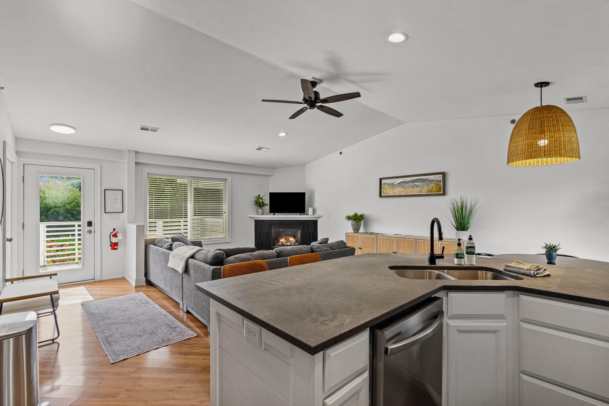 Open-plan kitchen and living room with a large gray island, sectional sofa, and fireplace.