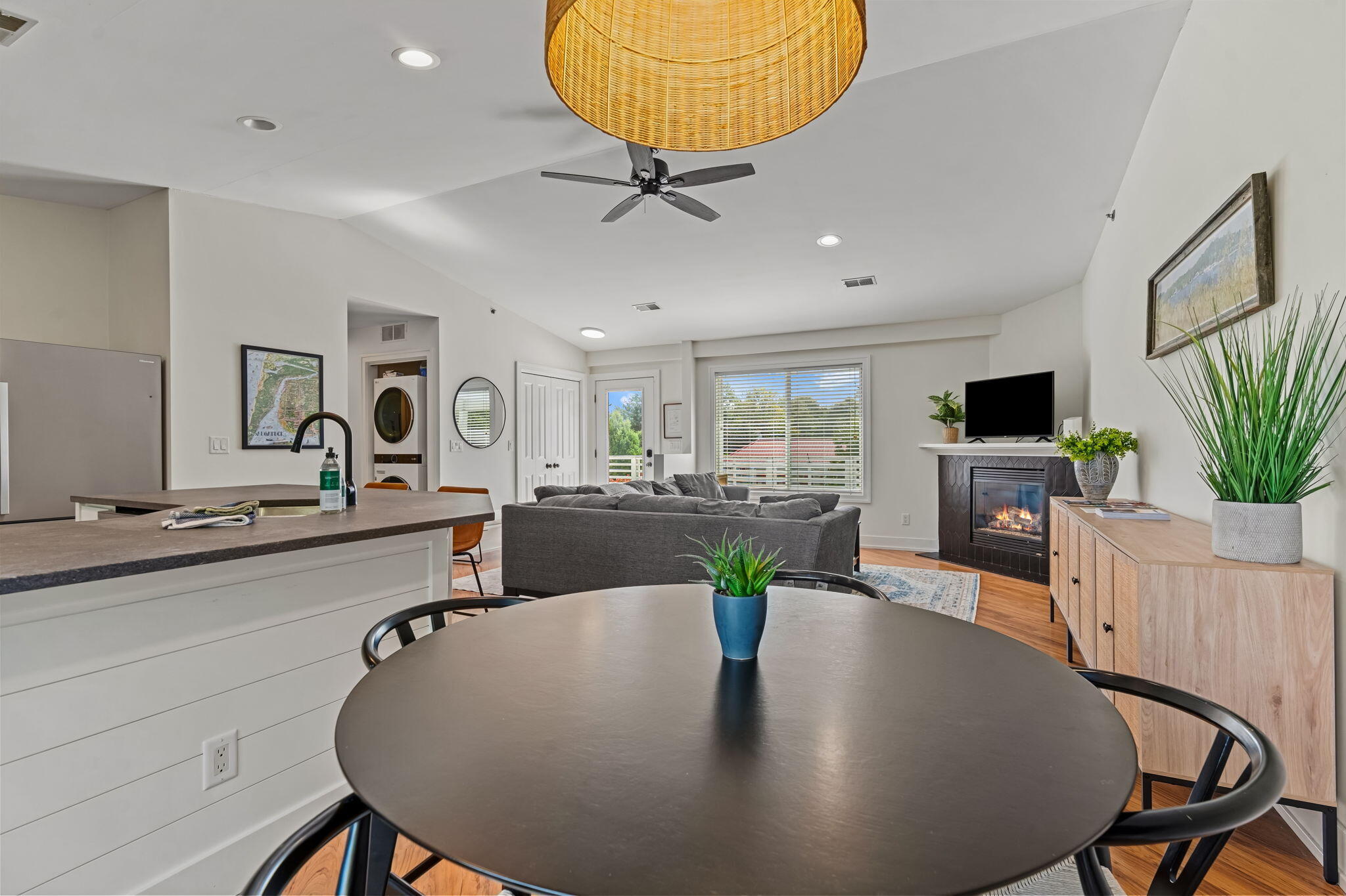 Open-plan living and dining room with a kitchen island, gray sofa, and fireplace.