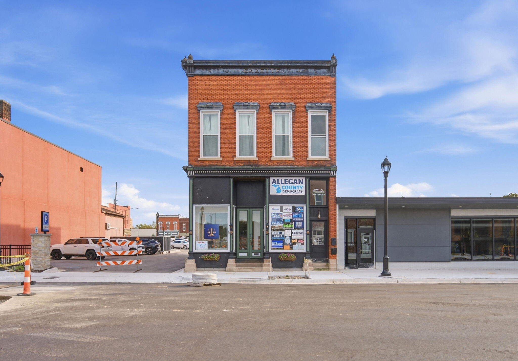 Two-story red-brick downtown storefront with tall upper windows and Allegan County Democrats signage.