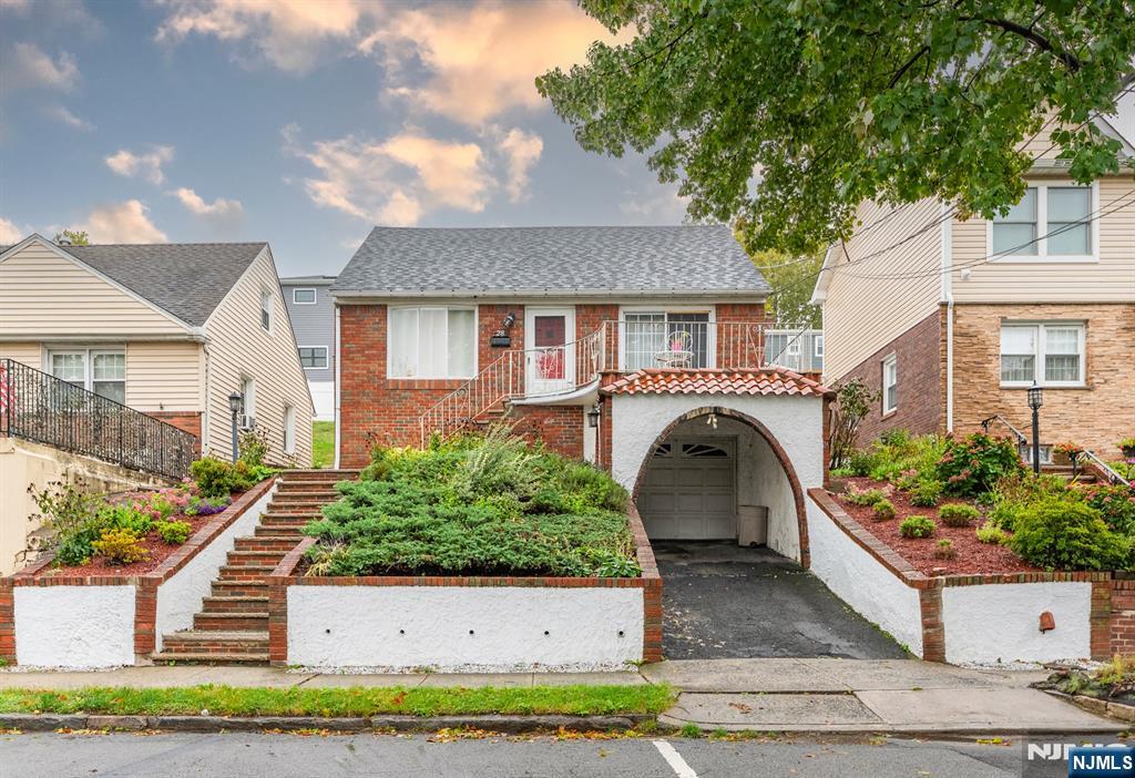 Brick house with landscaped steps and an arched driveway entrance to the garage.