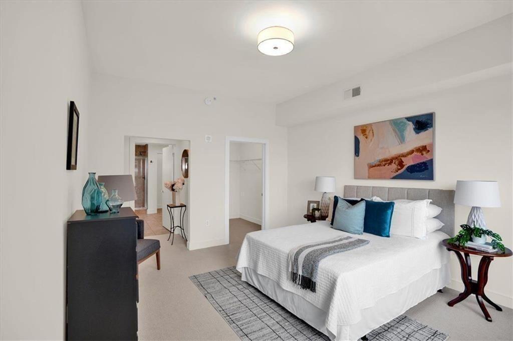 Staged bedroom with a king-size bed, blue accent pillows, and abstract artwork above the headboard.