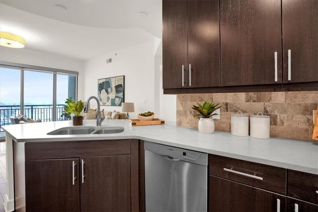 Modern condo kitchen with dark wood cabinets, stone counters, and sliding doors to a balcony.