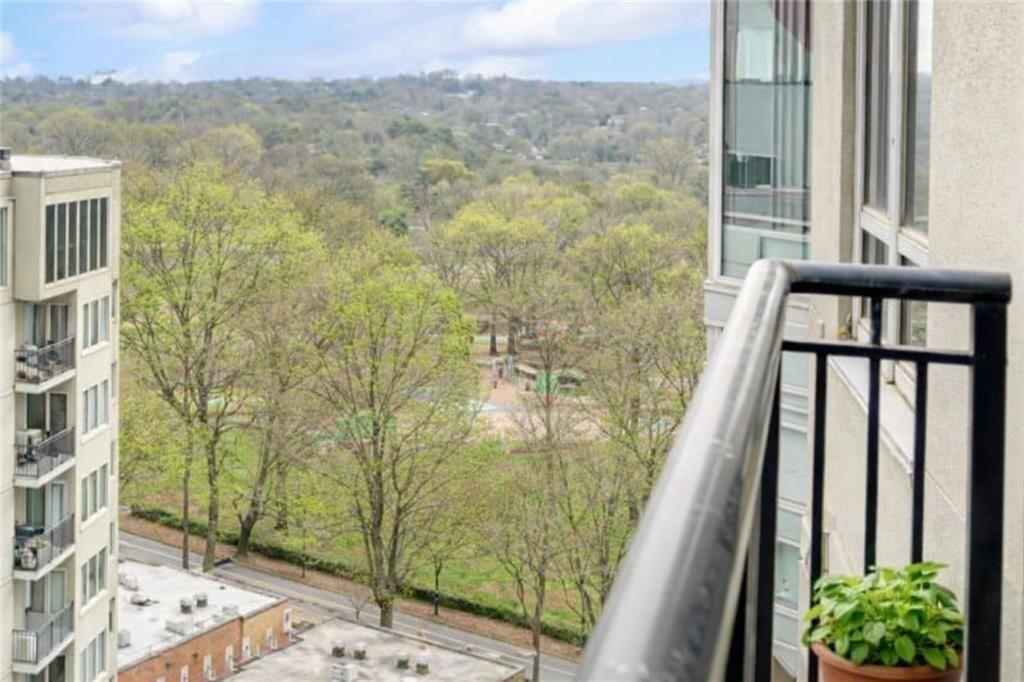 Apartment balcony overlooking a leafy park and wooded hills.