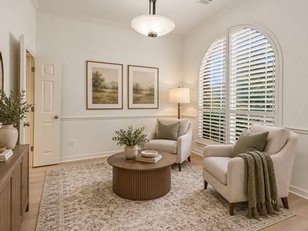Living room with two armchairs, a round coffee table, and an arched window with white shutters.