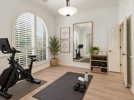 Home exercise room with an exercise bike, arched shuttered window, and workout mat.