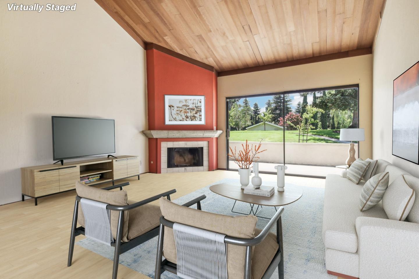 Virtually staged living room with a vaulted wood ceiling, red fireplace wall, and sliding glass doors to a green lawn.