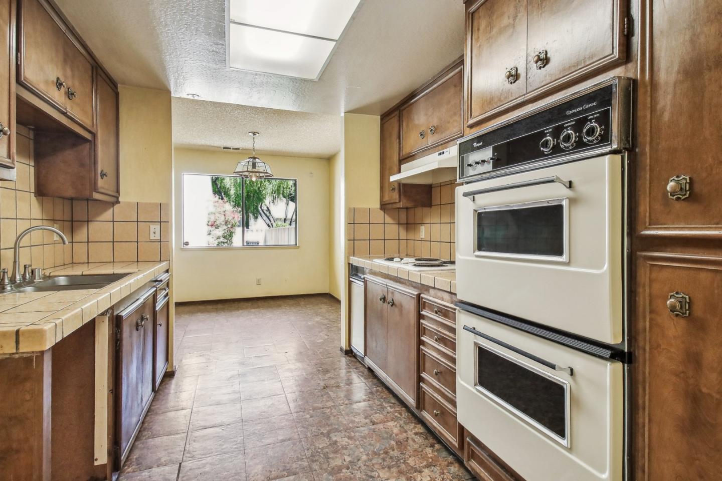 Kitchen with dark wood cabinets, tile counters, and a double wall oven.