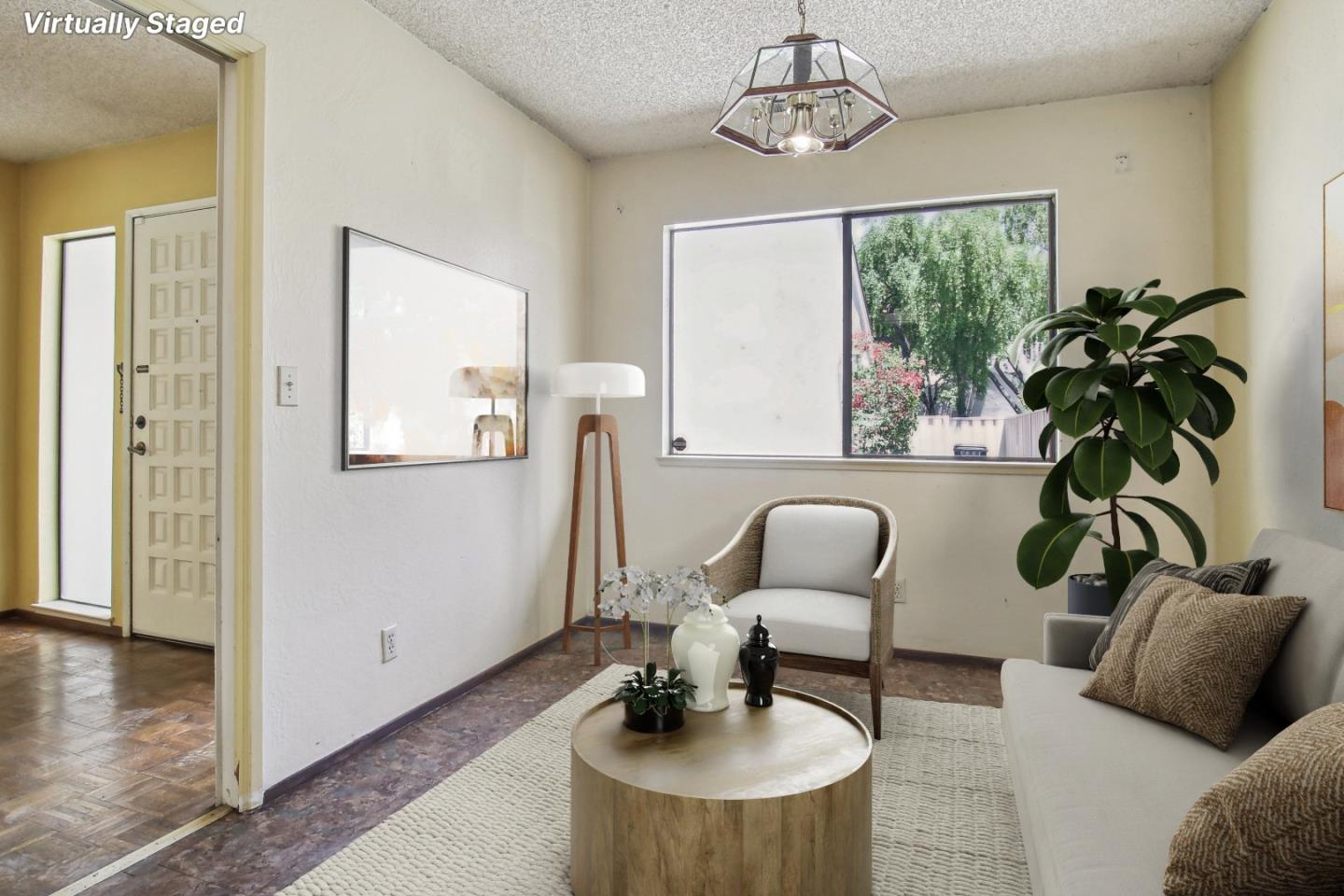 Virtually staged living room with a white sofa, accent chair, round coffee table, and large window.