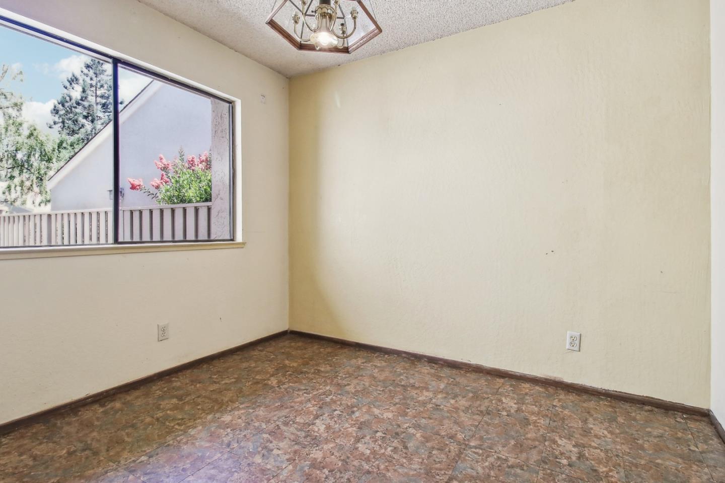 Empty room with mottled tile flooring and a large window overlooking a deck.