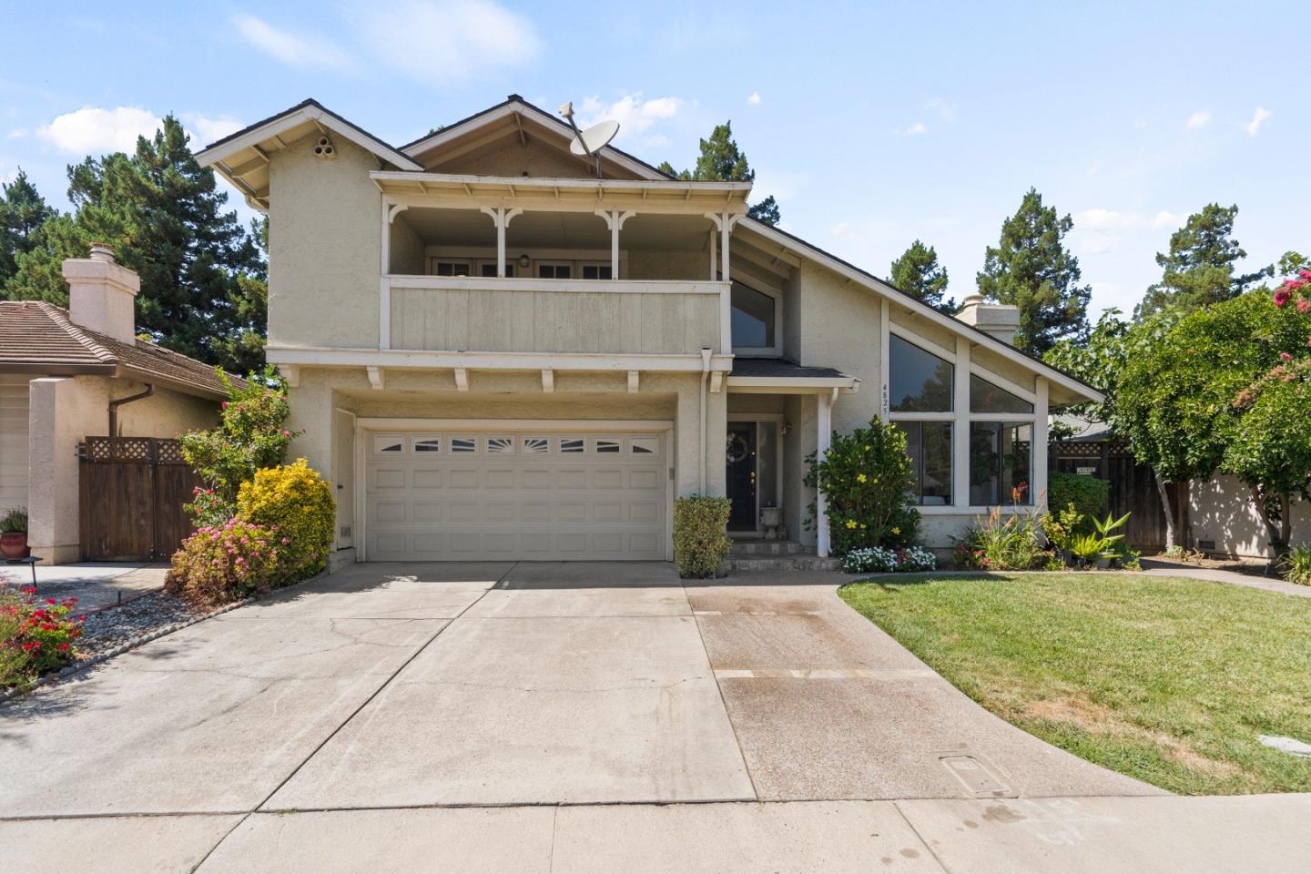 Two-story house with a covered balcony, double garage, and broad driveway.