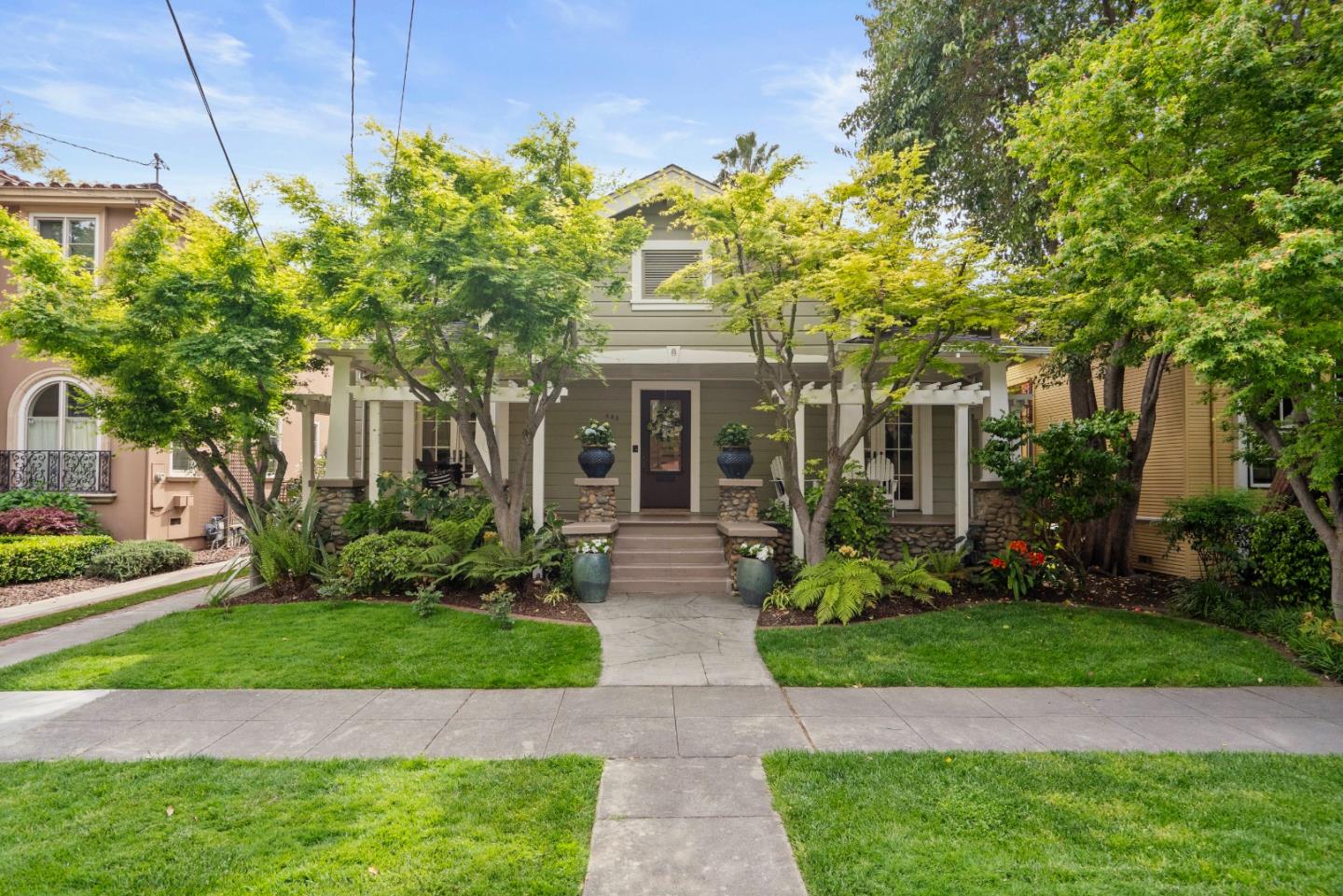 Gray two-story house with a covered porch, stone columns, and a landscaped front yard.