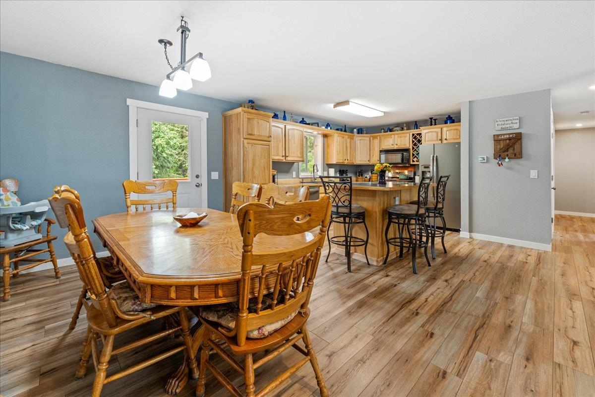 Wooden dining table beside a kitchen with light cabinets and a breakfast bar.