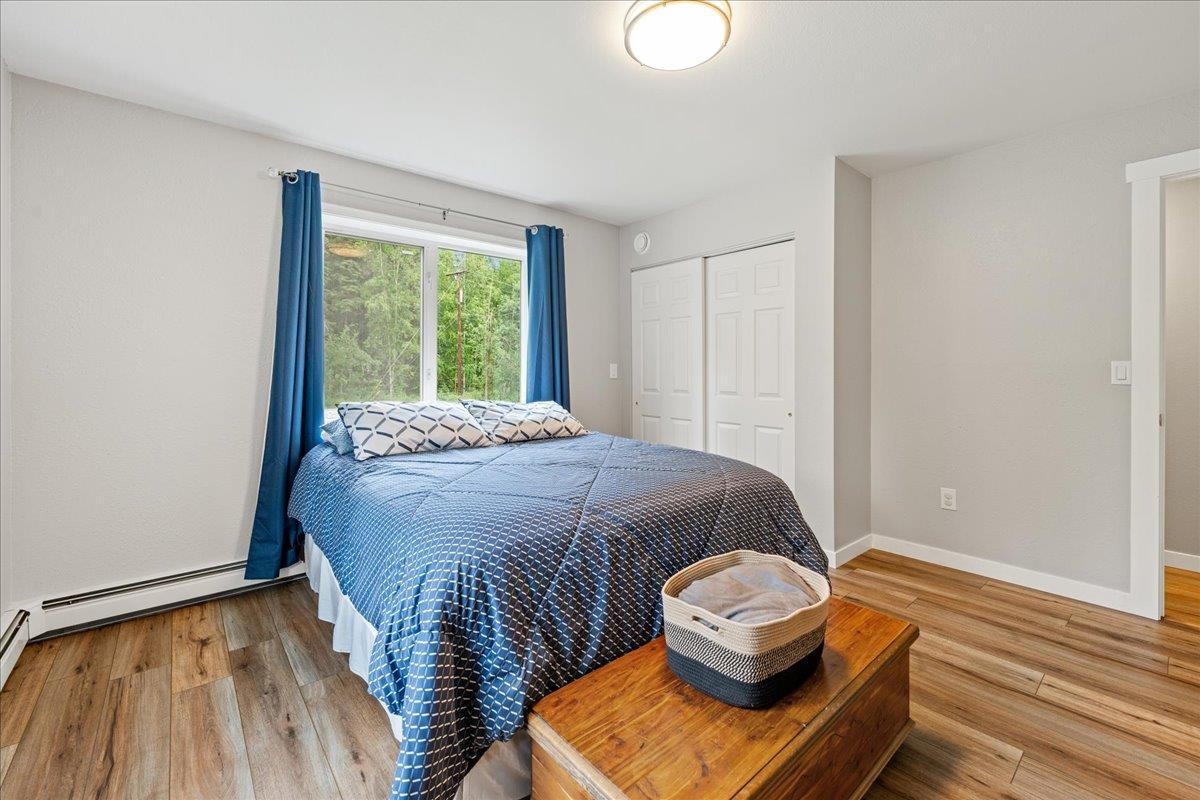 Bedroom with a blue-quilted bed, blue curtains, and a window overlooking trees.