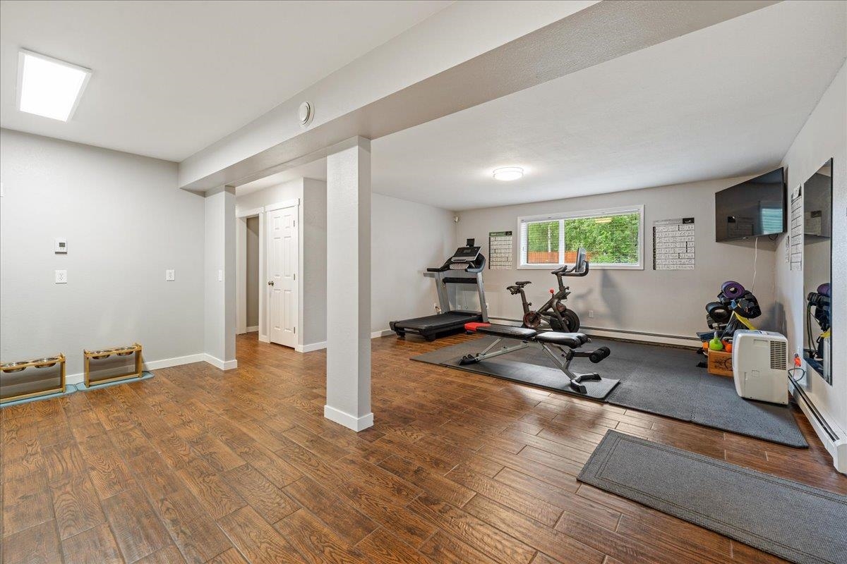 Exercise room with workout equipment on a large mat and a window overlooking greenery.