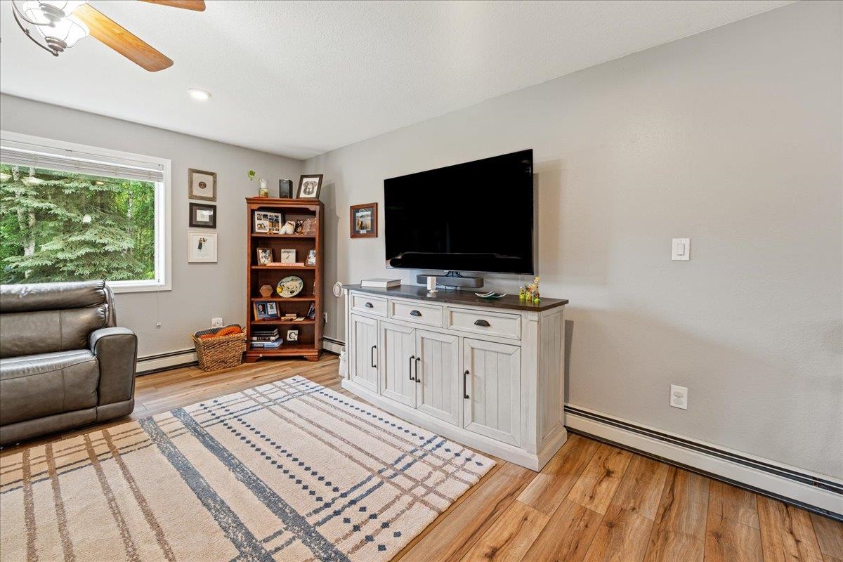 Living room with a television, white media cabinet, leather recliner, and a window overlooking trees.