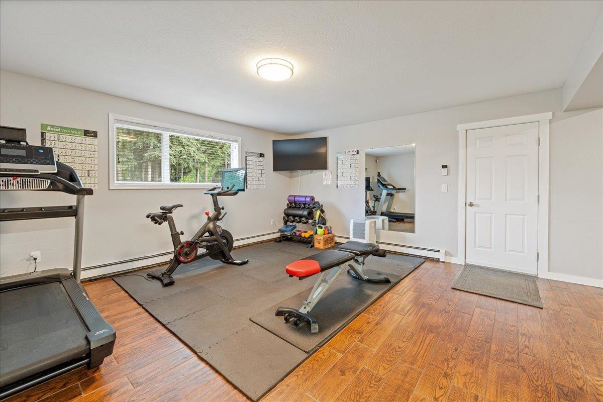 Home gym with a treadmill, stationary bike, weights, and bench on a large workout mat.
