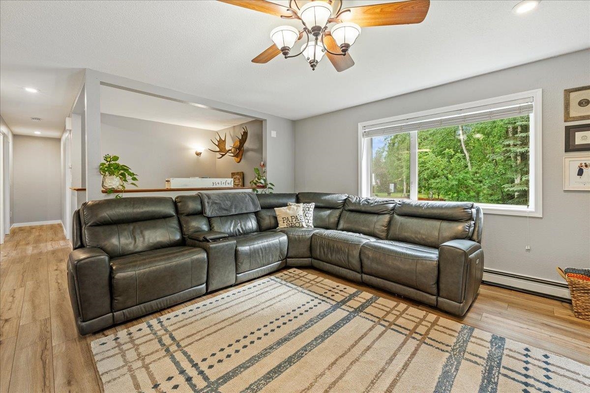 Living room with a dark leather sectional, patterned rug, and wide window overlooking trees.