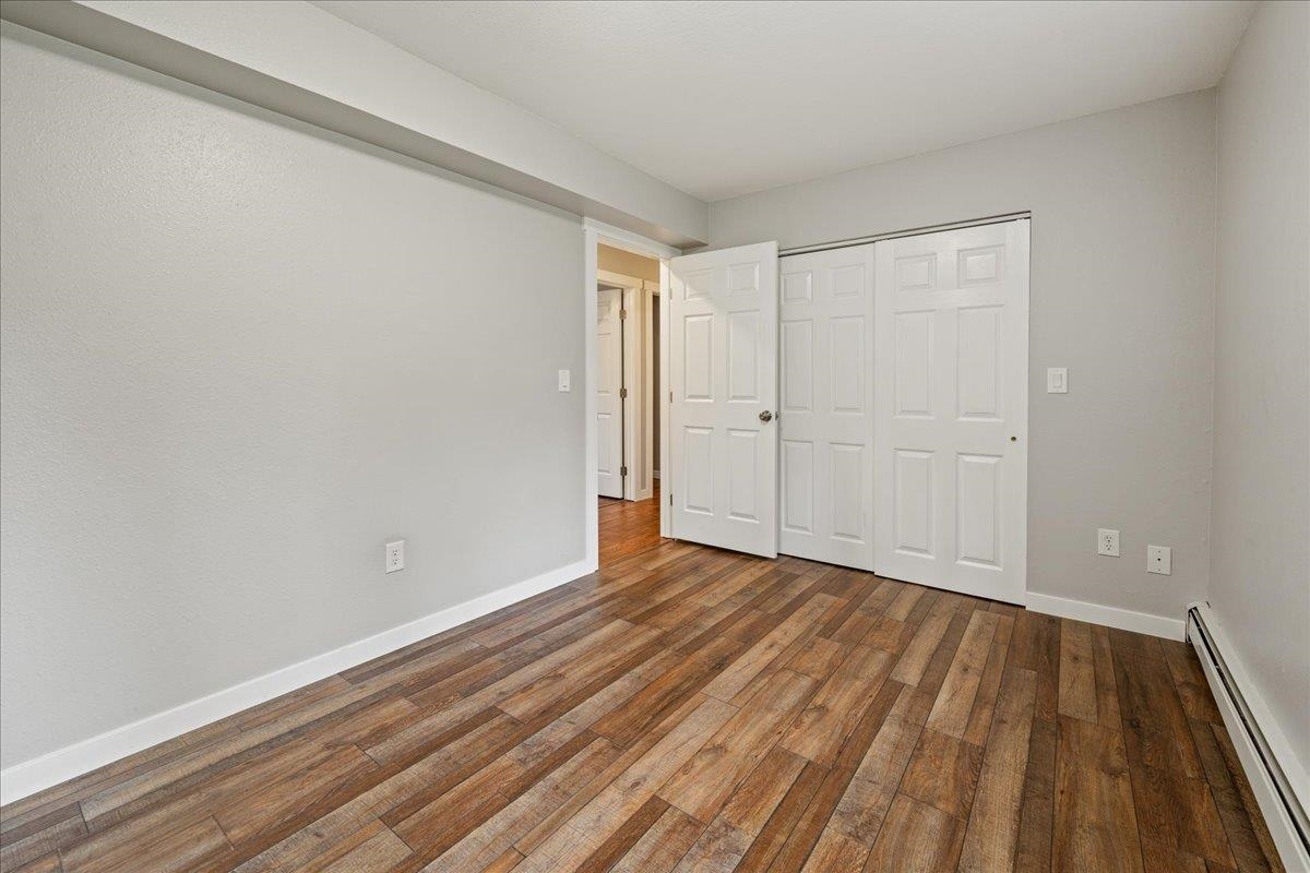 Empty bedroom with wood-look plank flooring and white closet doors.