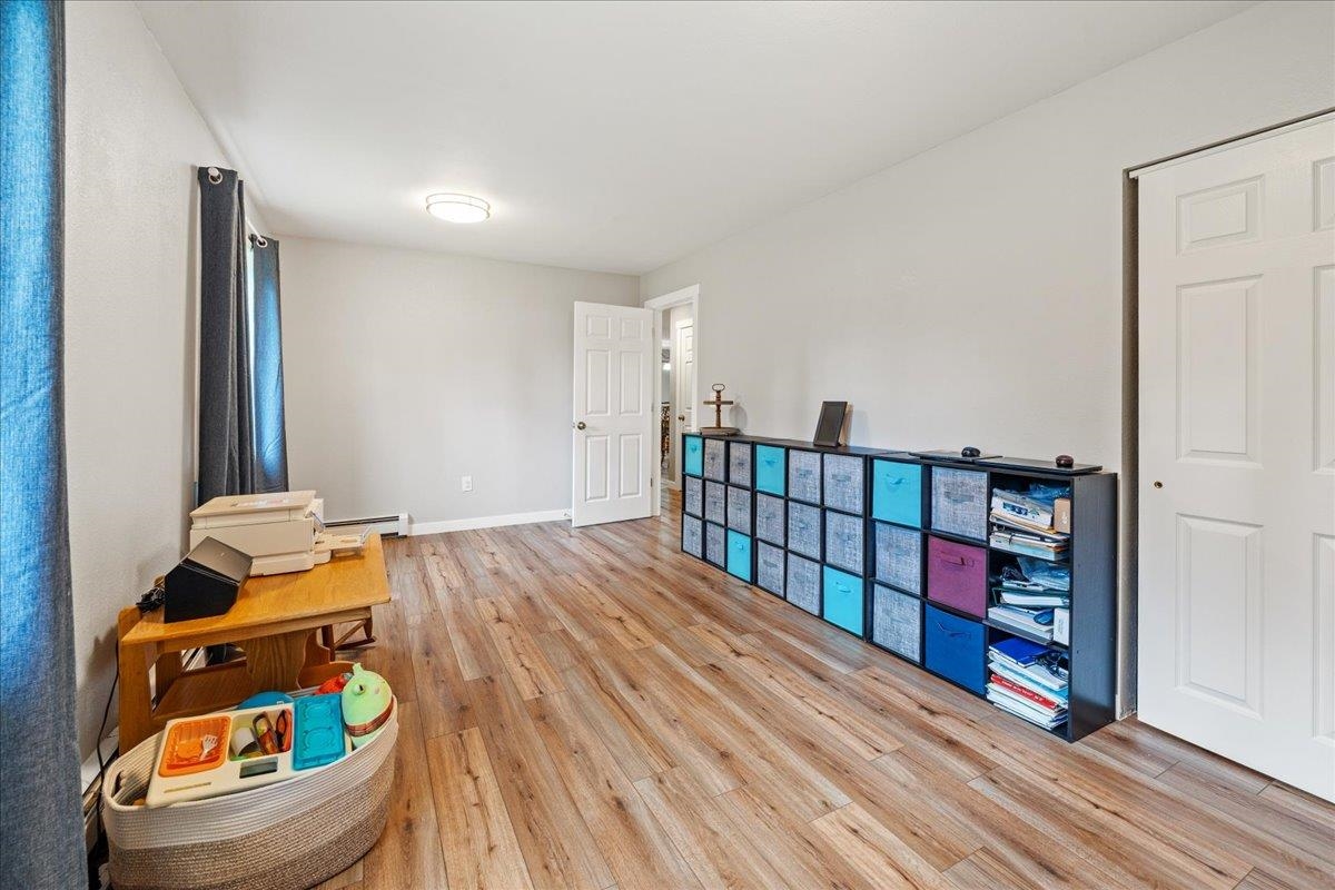 Bright room with wood-look floors, colorful storage bins, blue curtains, and a toy basket.