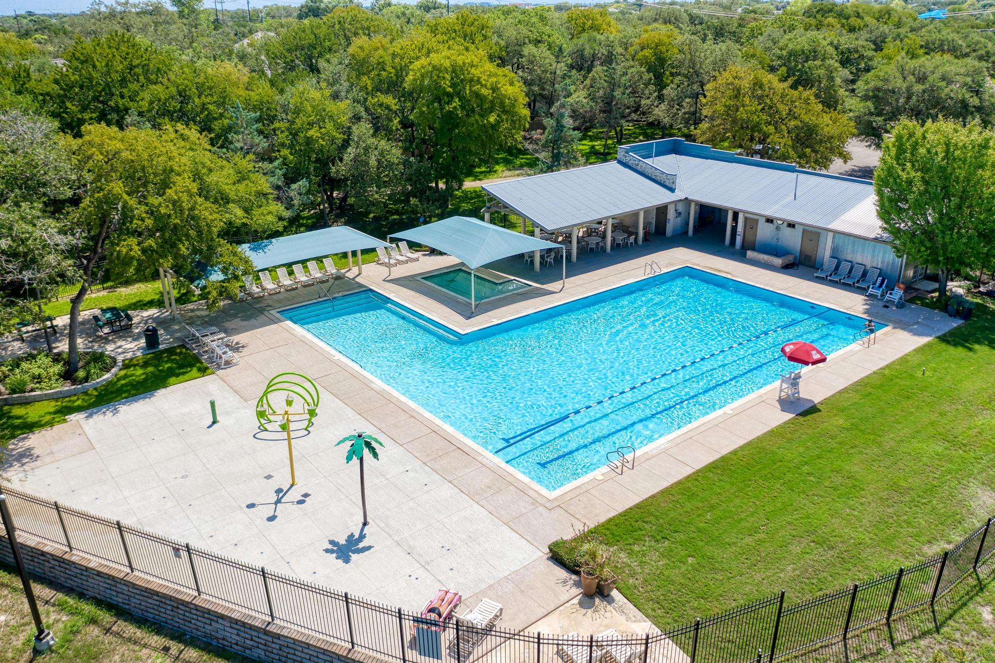 Aerial view of a large outdoor pool with shaded seating and lounge chairs.