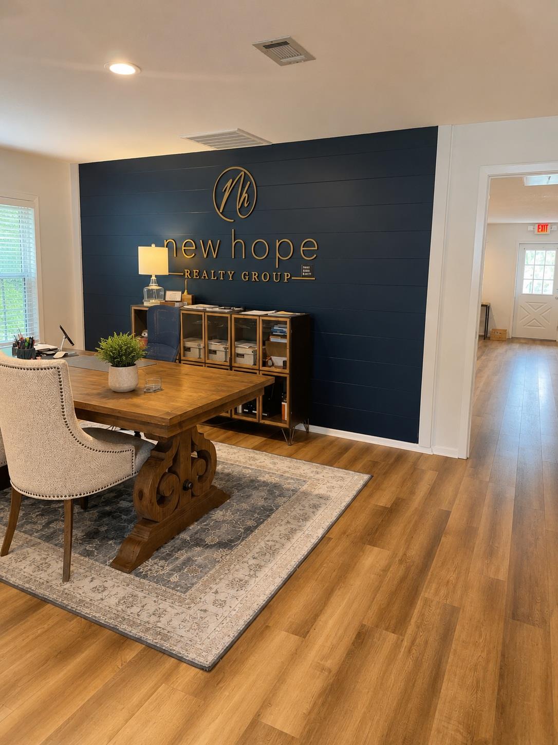 Furnished office with a wooden desk and New Hope Realty Group lettering on a navy wall.