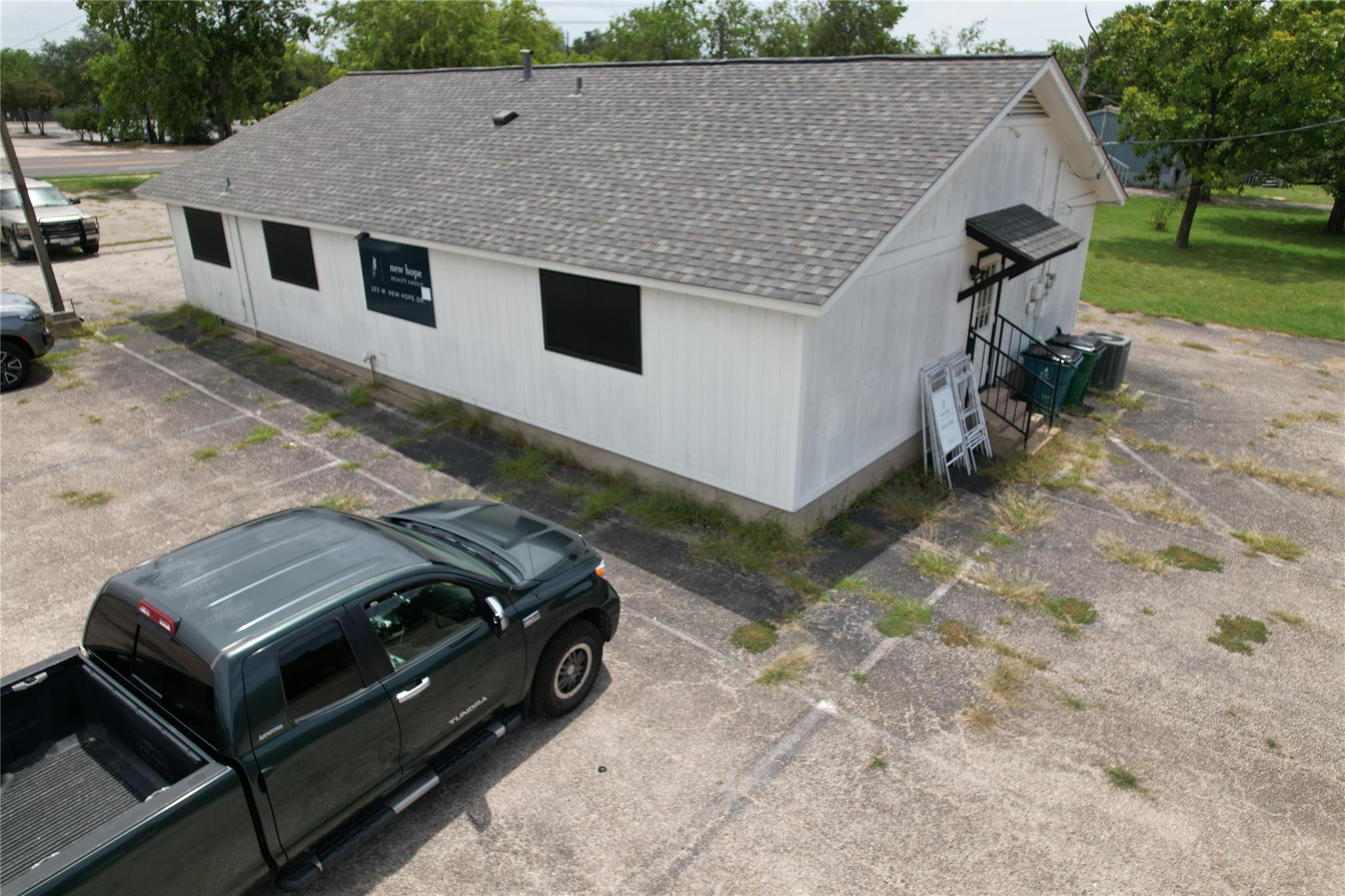 Small white office building with a gray gable roof, New Hope Realty Group sign, and surrounding parking lot.