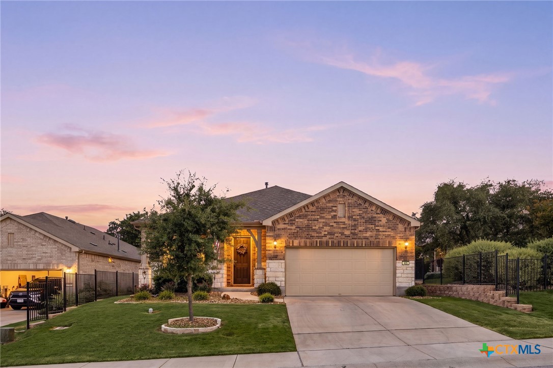 Brick-and-stone house with an attached garage and landscaped front lawn at dusk.