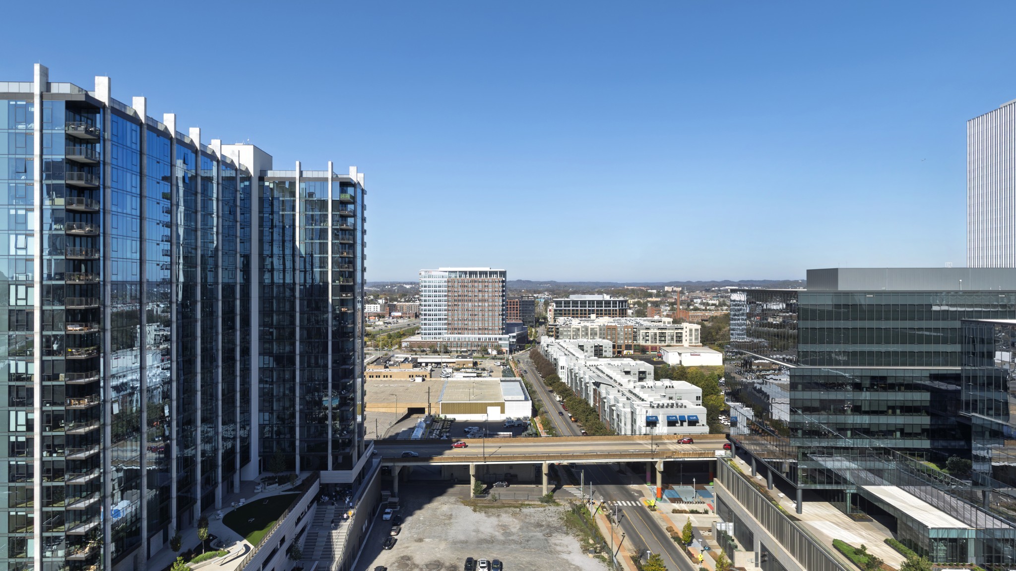 Elevated downtown Nashville view framed by glass high-rises beneath a clear blue sky.
