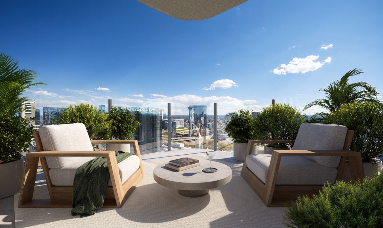 Furnished terrace with lounge chairs and potted greenery overlooking the city skyline.