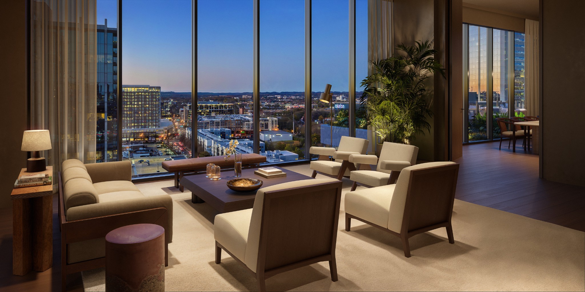Furnished condo living room with floor-to-ceiling windows overlooking the Nashville skyline at dusk.
