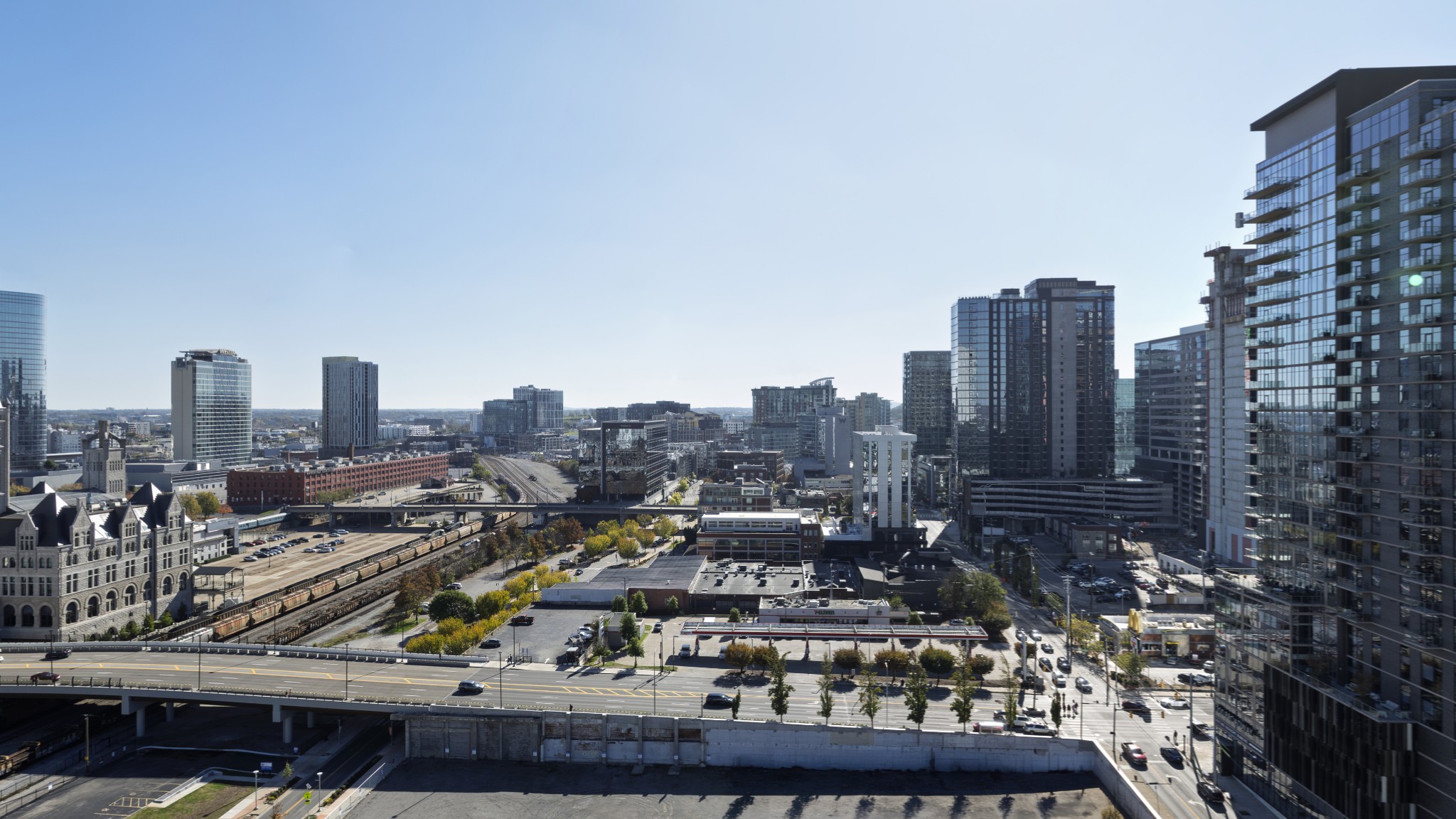 Downtown Nashville skyline with high-rise towers, railway tracks, and an elevated highway below.