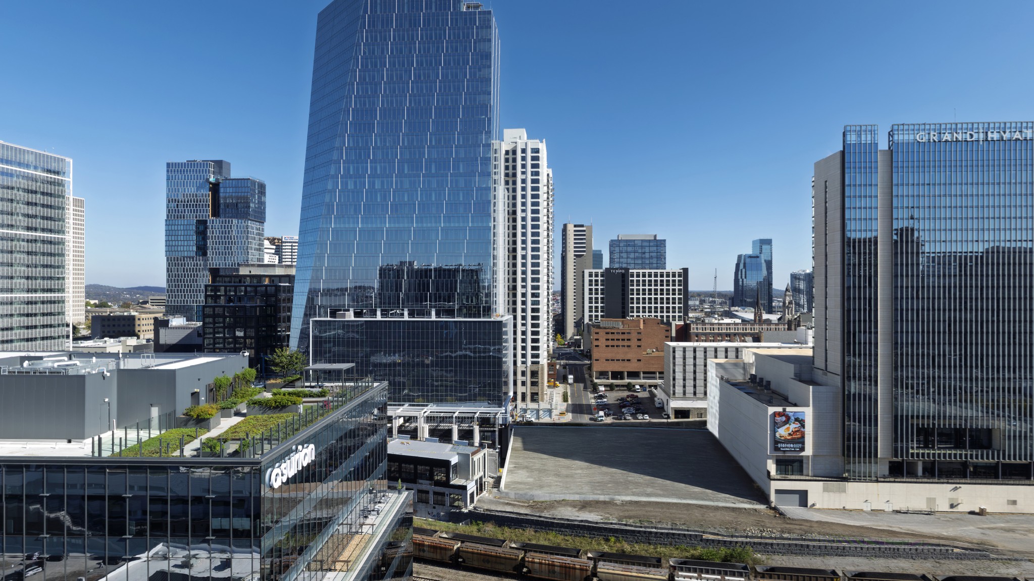 Downtown Nashville skyline with glass towers and a landscaped rooftop terrace in the foreground.
