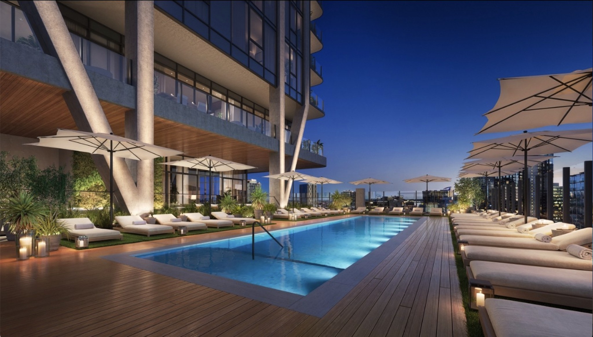 Rooftop pool beside a modern high-rise, surrounded by lounge chairs and umbrellas with city buildings beyond.