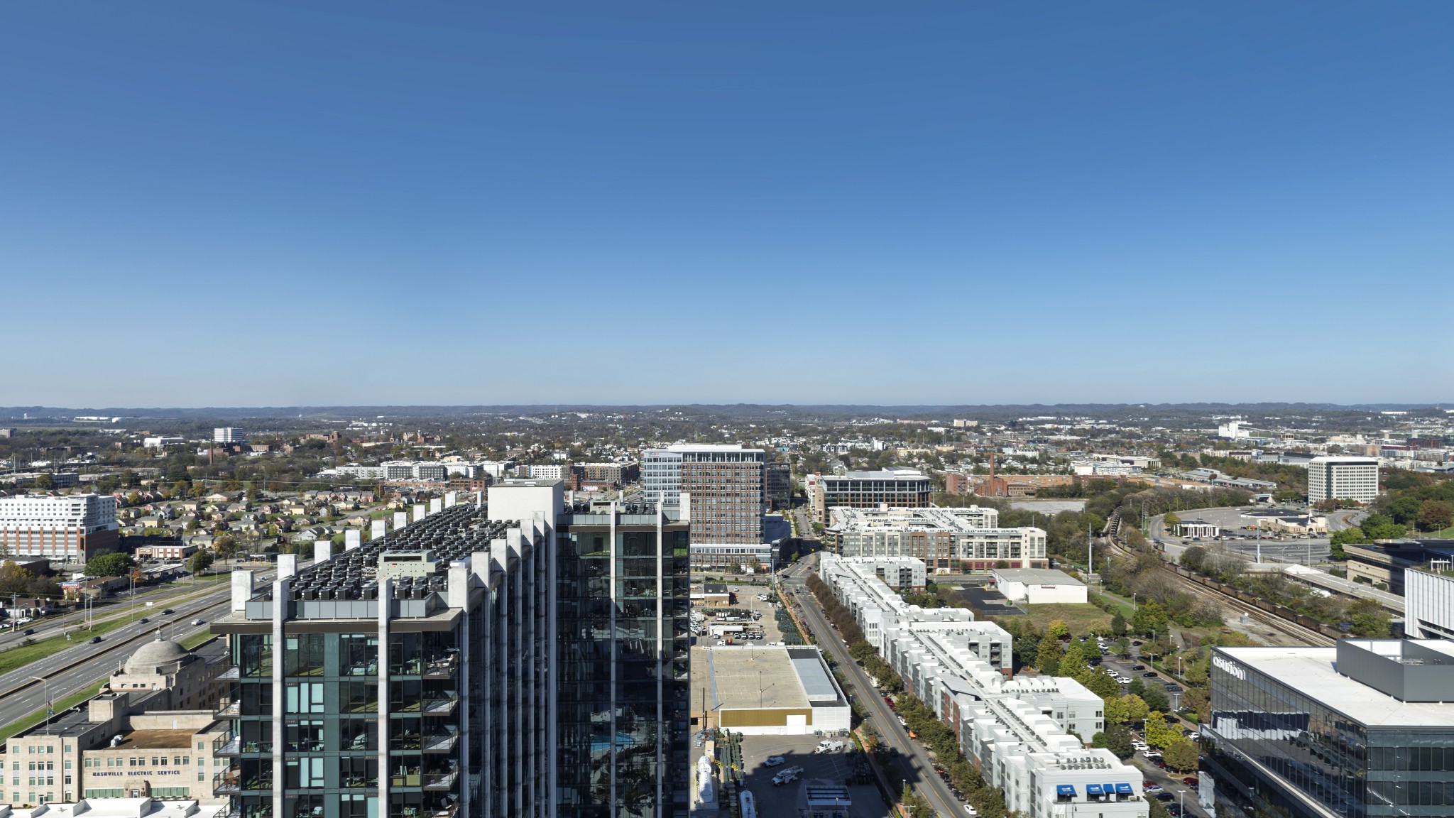Panoramic Nashville city view with modern high-rises, roads, and rail lines.