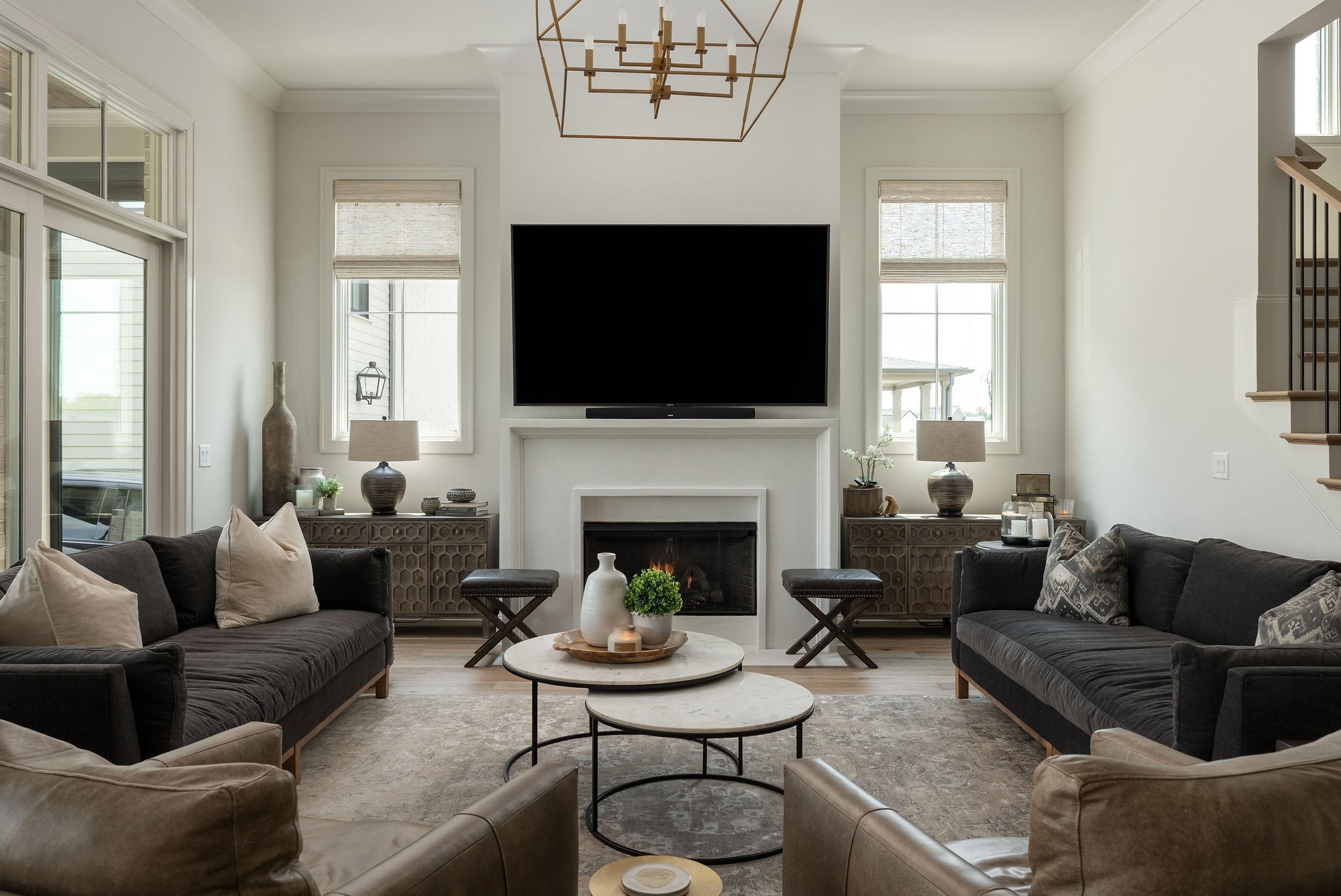 Furnished living room with dark sofas, a white fireplace, and a television above the mantel.