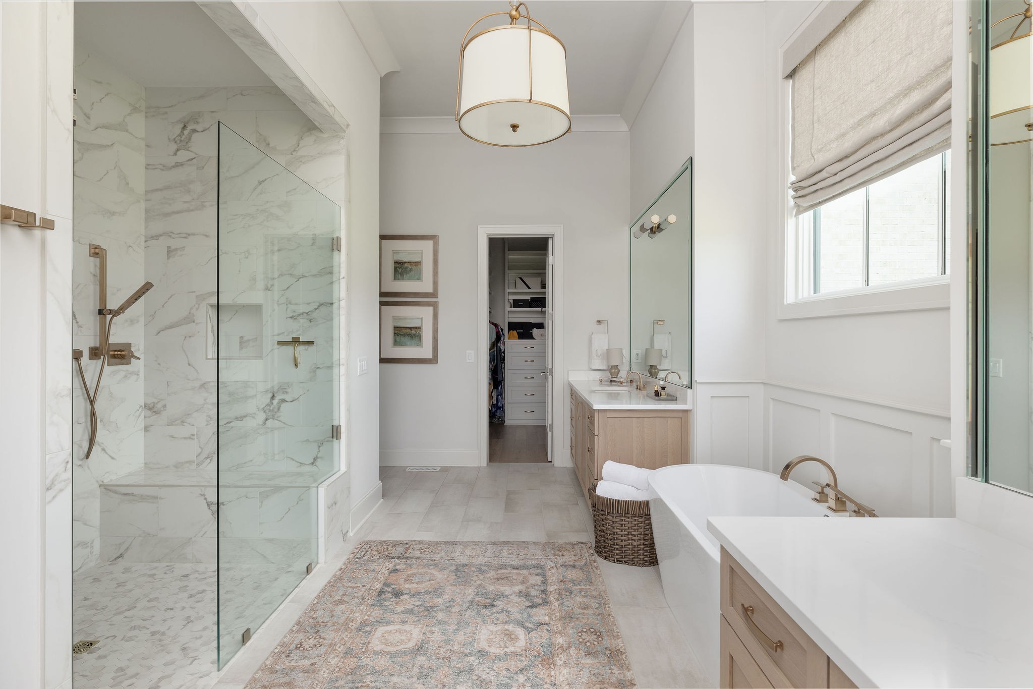 Primary bathroom with a marble walk-in shower, freestanding tub, and light wood double vanity.