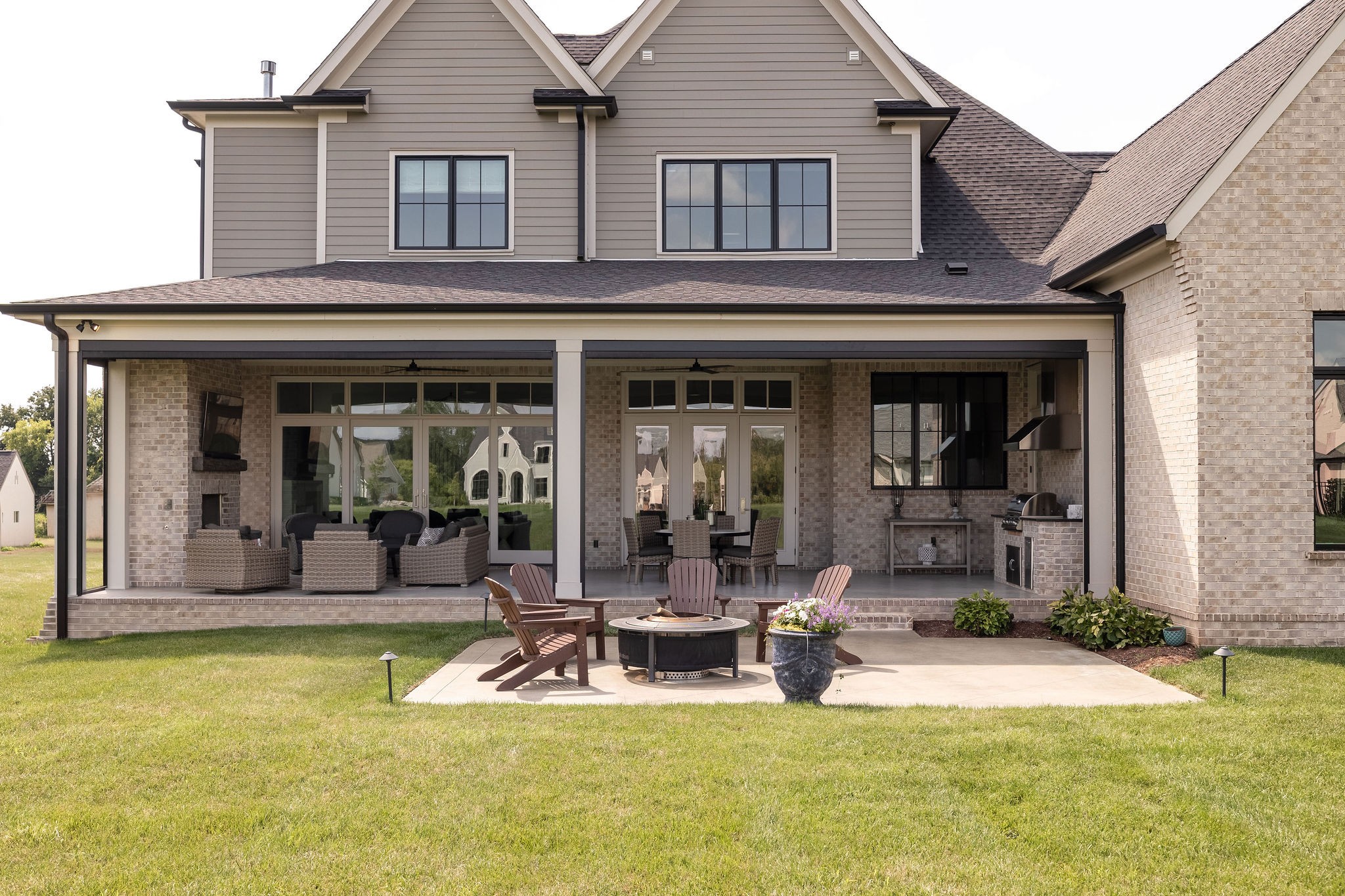 Rear of a two-story home with a furnished covered patio and an outdoor fire pit.