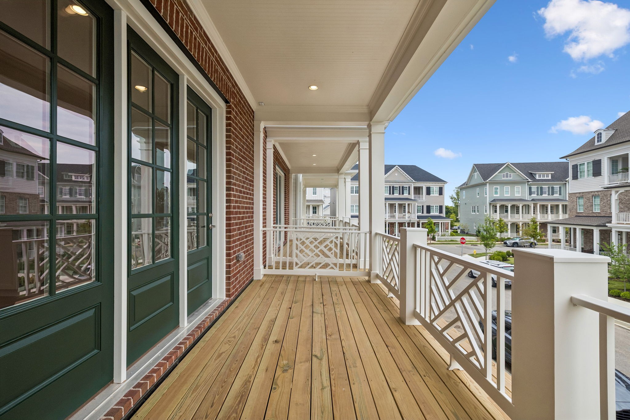 Covered porch with wood decking and white railings overlooking neighboring homes.