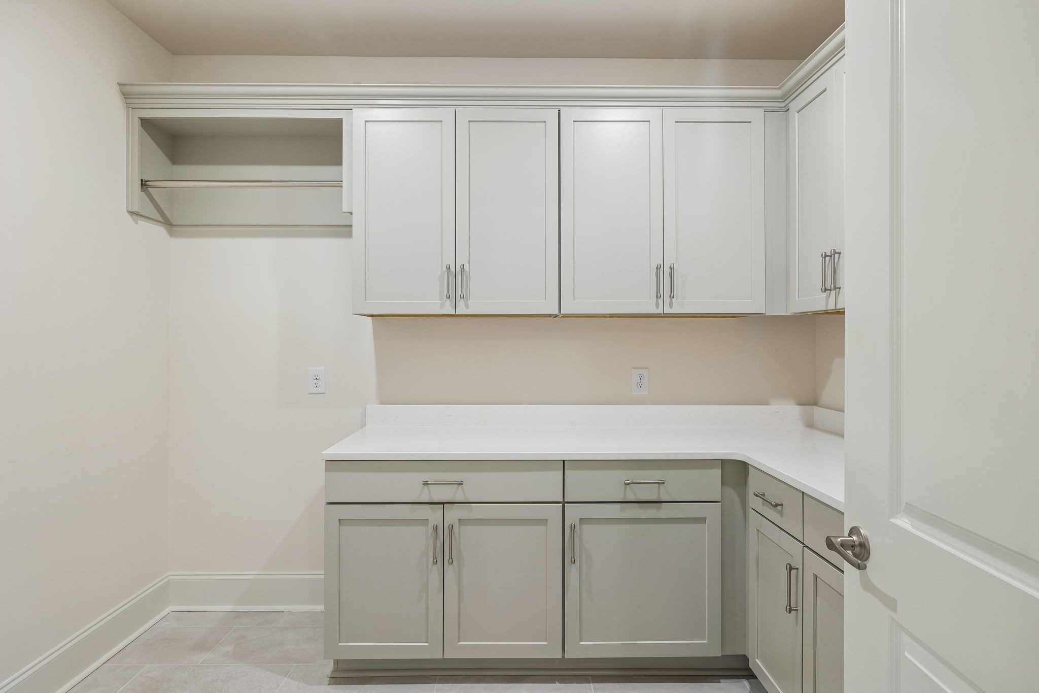 Vacant pantry with white built-in cabinets, an L-shaped counter, and an open shelf.