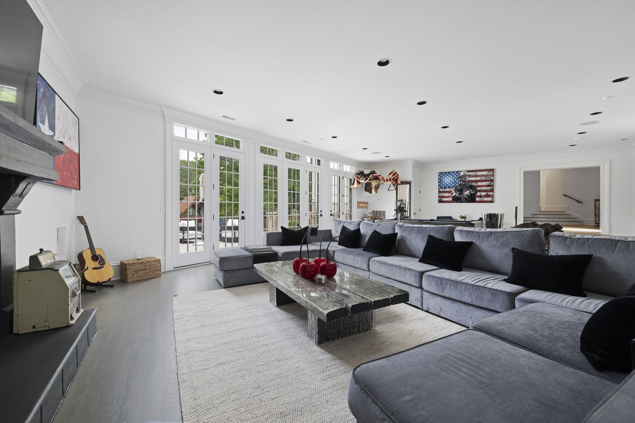 Living room with a gray sectional, stone coffee table, and tall French doors opening to a patio.